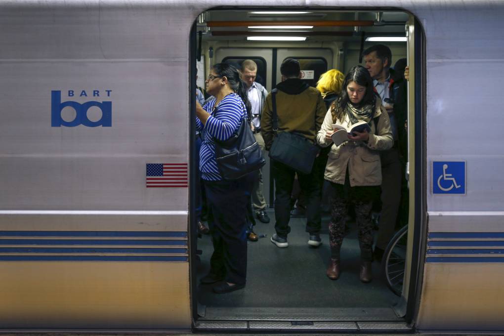 People are seen through the open doorway of a train car.