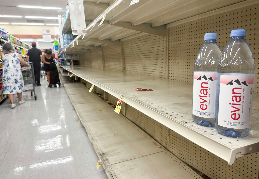 Empty shelves with just two bottles of Evian water left in a supermarket aisle.