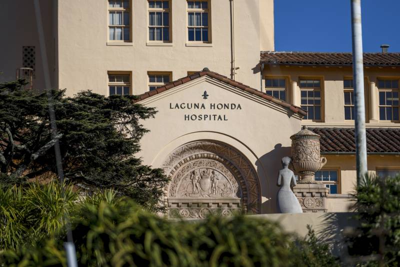 Signage reading Laguna Honda Hospital over entryway to a large tile-roofed building.