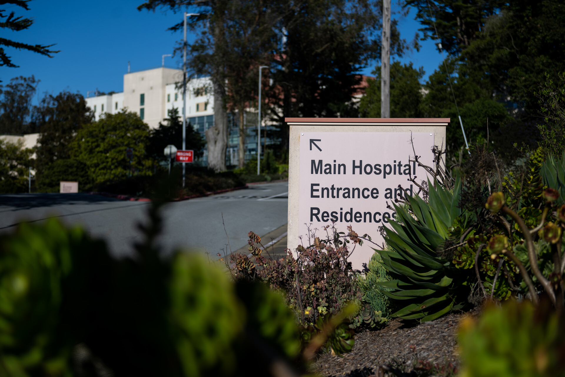 The entryway to a hospital driveway with a sign that reads, "Main Hospital Entrance and Residences."