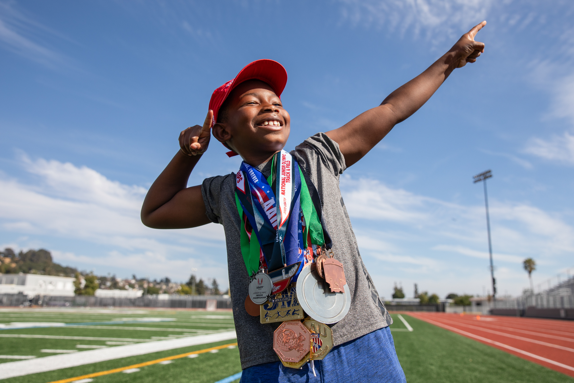 A boy poses for a photo with over ten medals hanging from around his neck.