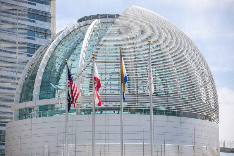 A domed building behind four flags on poles.