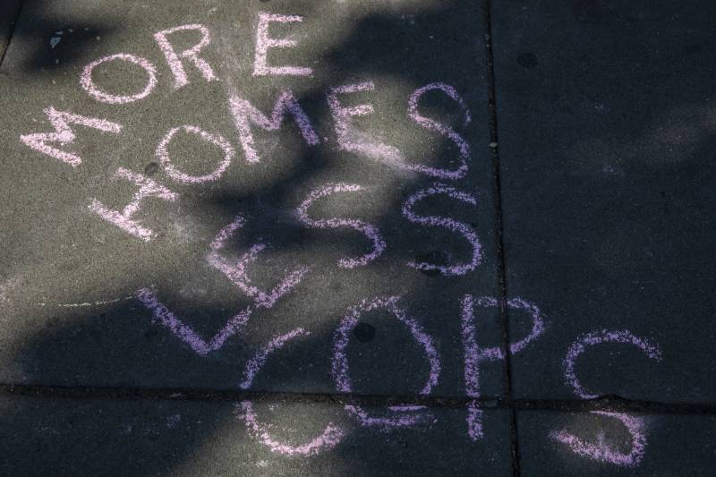 'More homes less cops' is written in pink chalk