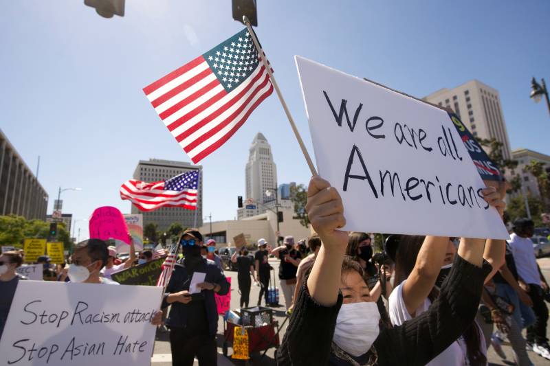 Several people standing with protest signs and American flags.
