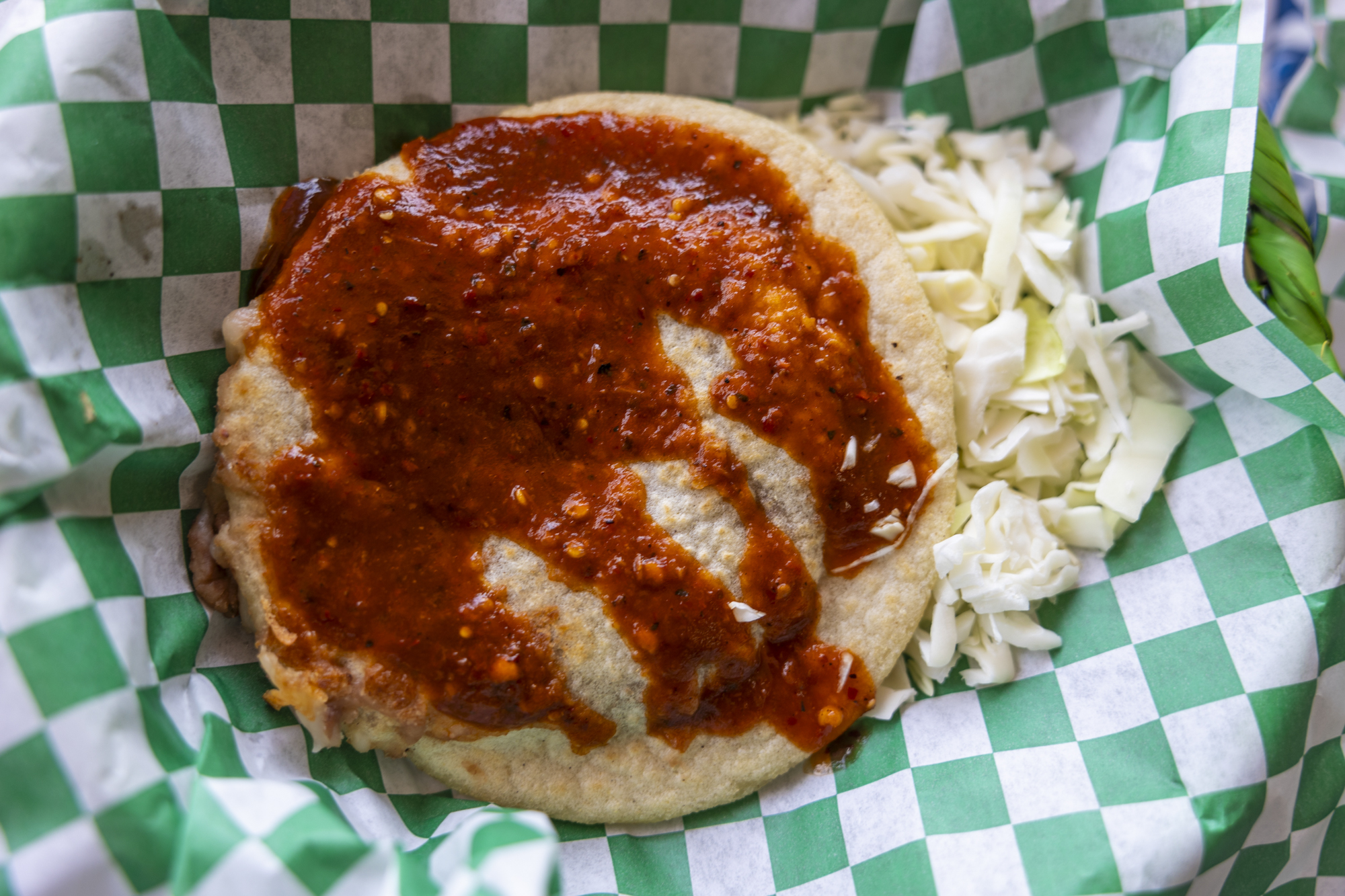 A picadillo gordita with salsa and shredded cabbage.