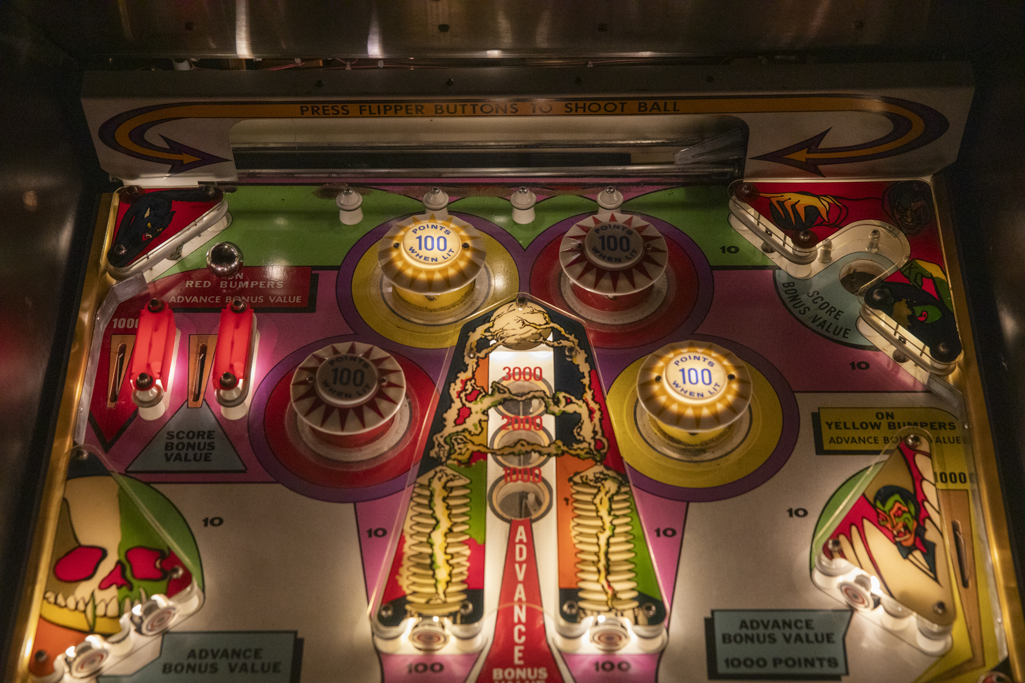 The lighted up display of a vintage pinball machine.