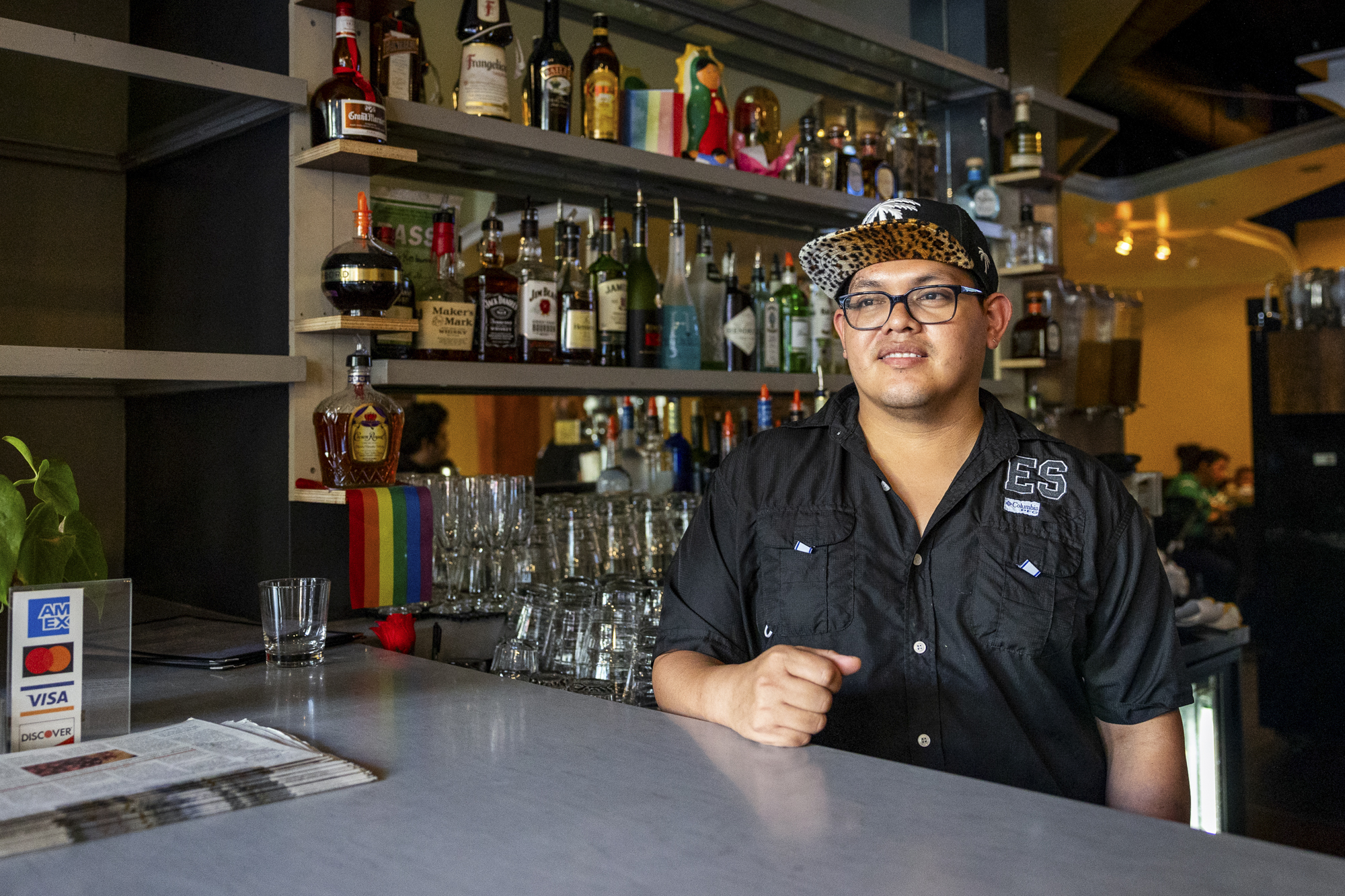 A person wearing a hat stands behind a bar.