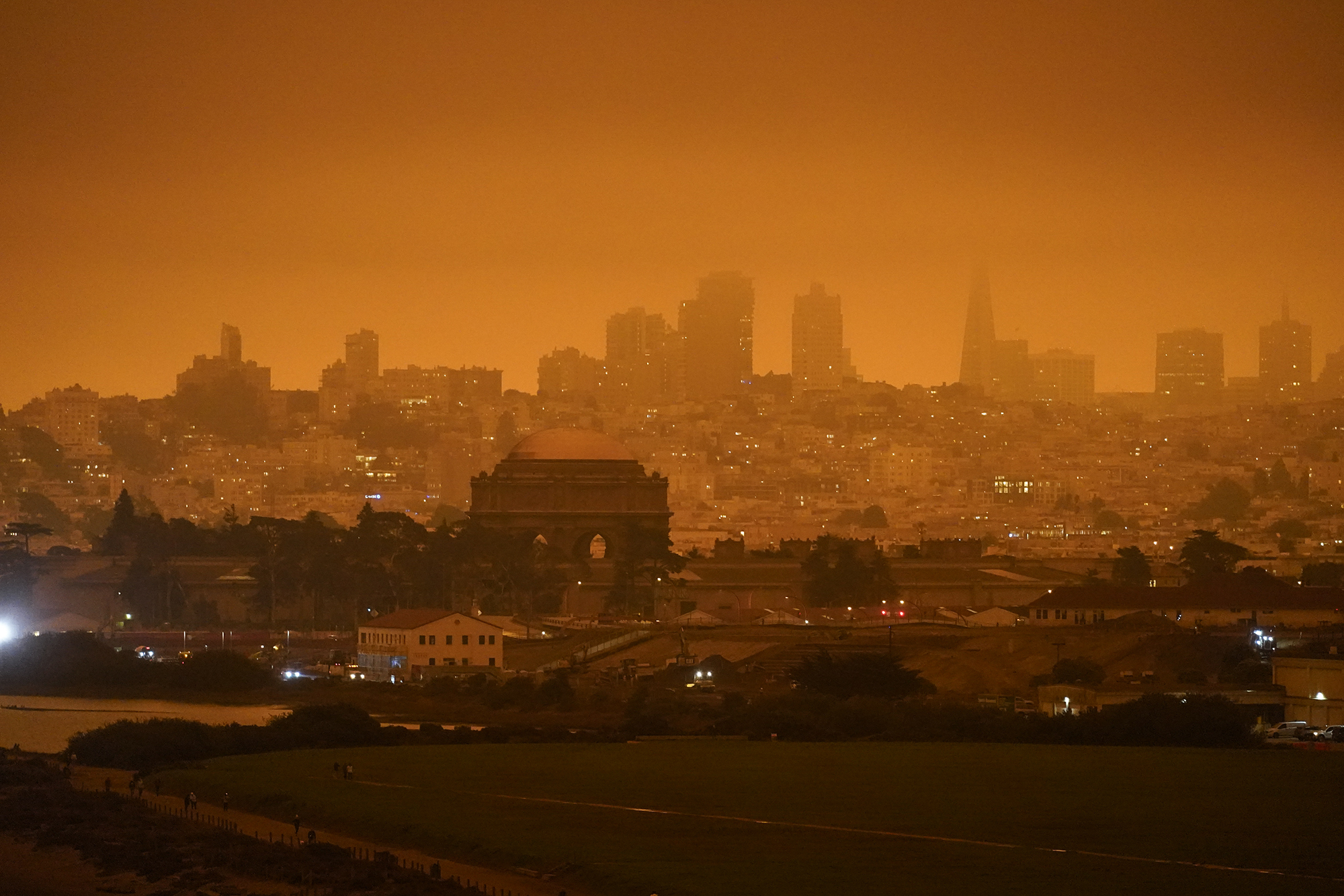 The San Francisco skyline is illuminated in a burnt, orange smog during wildfire season.
