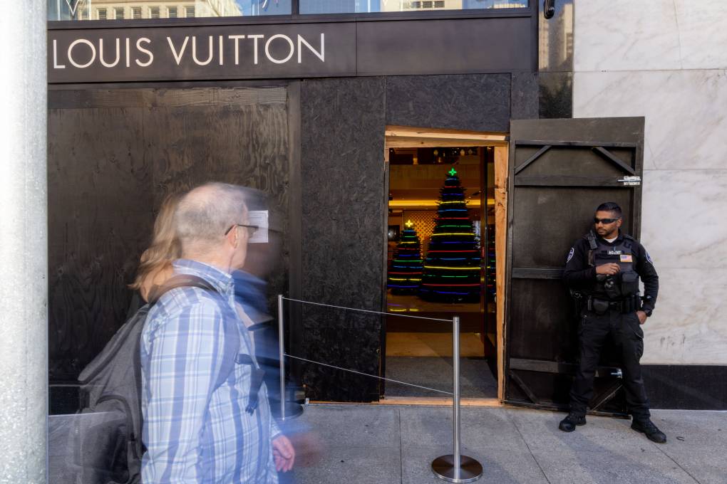 the boarded up windows of a Louis Vuitton store with a security guard out front