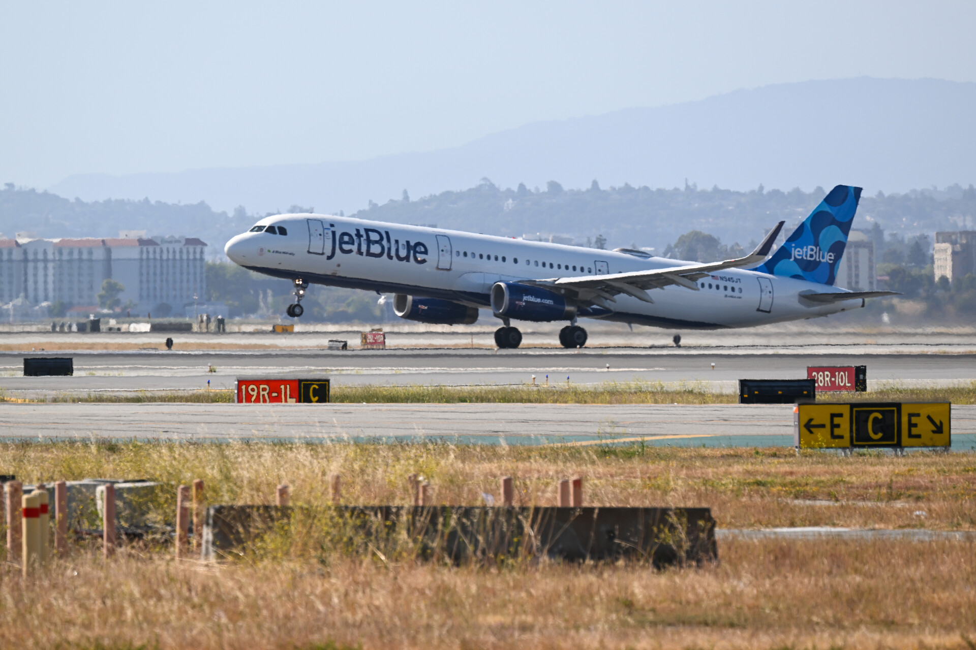 A passenger jet with JETBLUE on the side takes off from a runway.