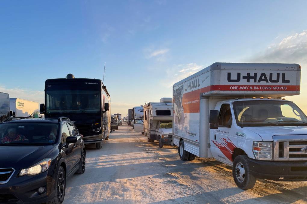 A U-Haul truck and many cars and other vehicles are lined up in a traffic jam in the Nevada desert as Burning Man festivalgoers prepare to leave the annual event.