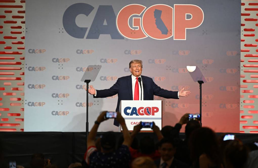 Donald Trump speaks in front of a lectern, with the words 'CAGOP' behind him.