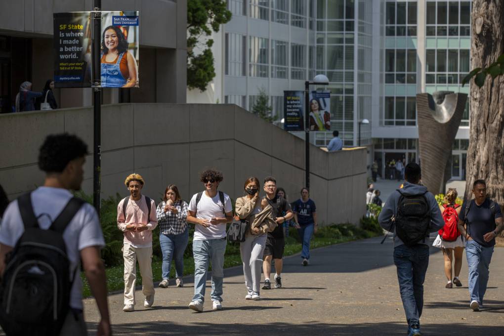 Young people walk outdoors on a college campus.