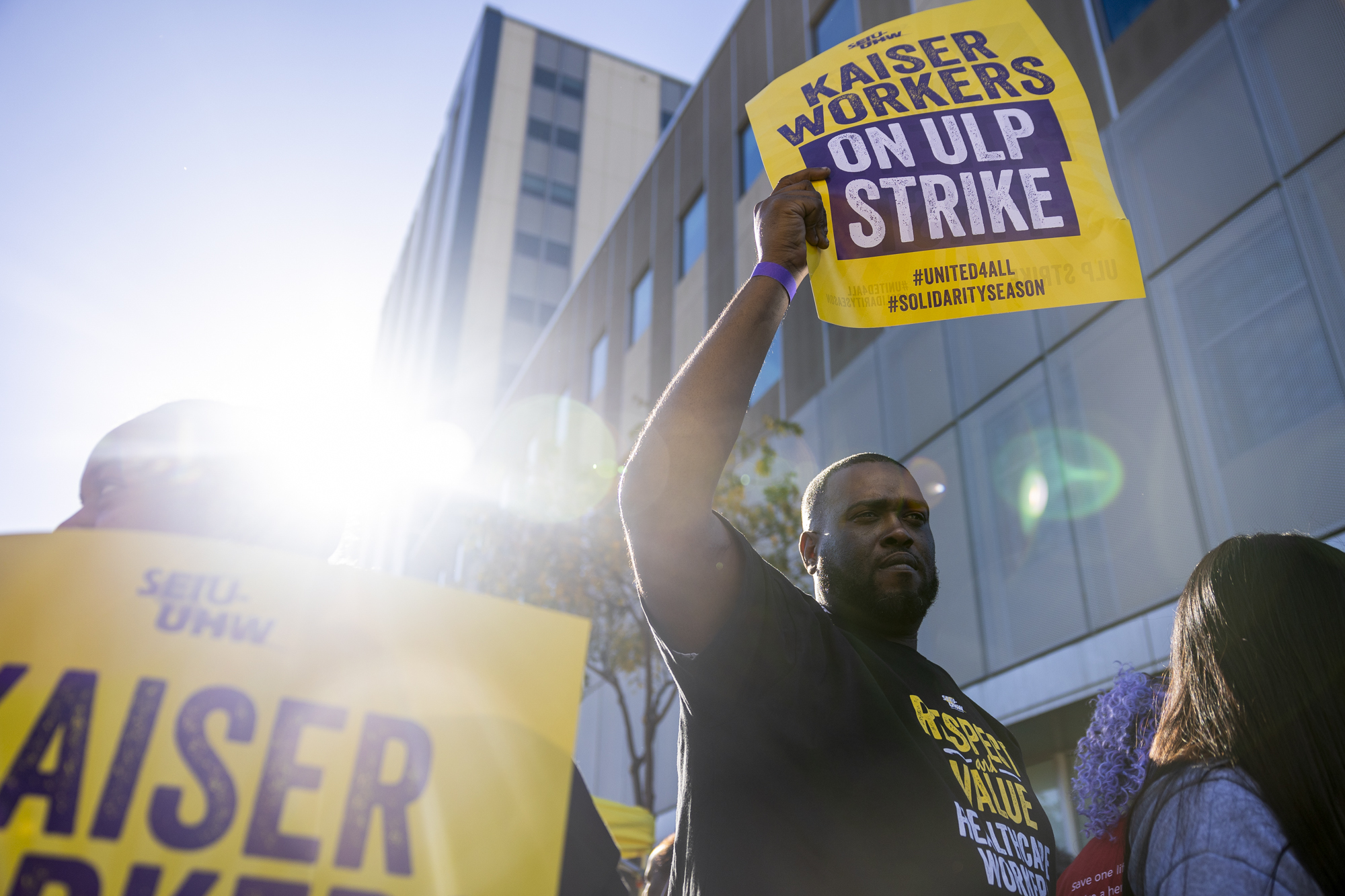 A person holds up a sign that reads "Kaiser Workers on ULP Strike."