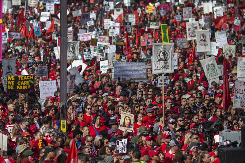 A large mass of people holding signs and wearing red.