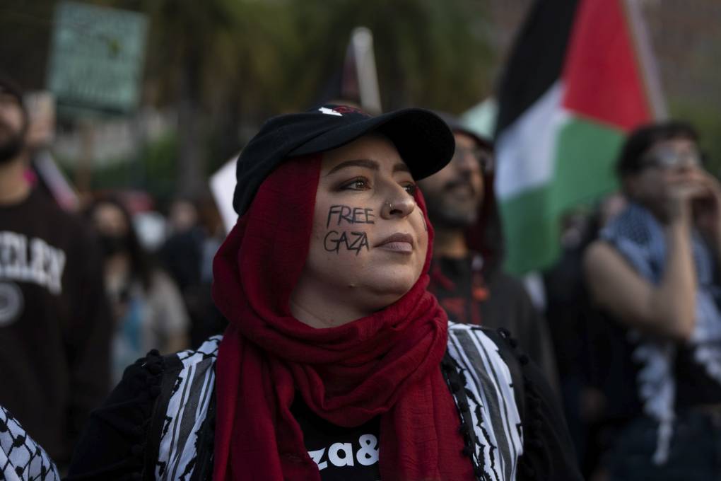 A person wearing a red headscarf with "Free Gaza" written on their cheek.