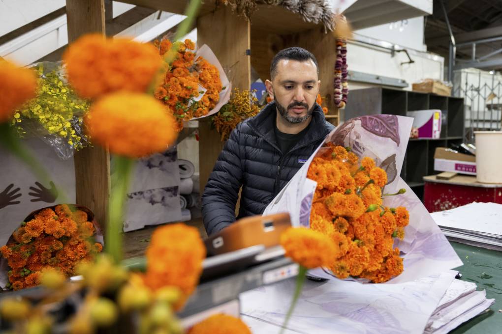 A person works wrapping marigolds in paper.