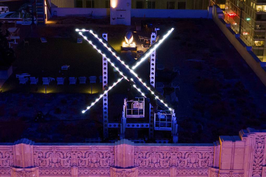 A brightly lit letter X is seen above a building.