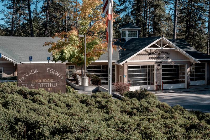 A building with a flag pole and a wooden sign that reads "Nevada County Consolidated Fire District"