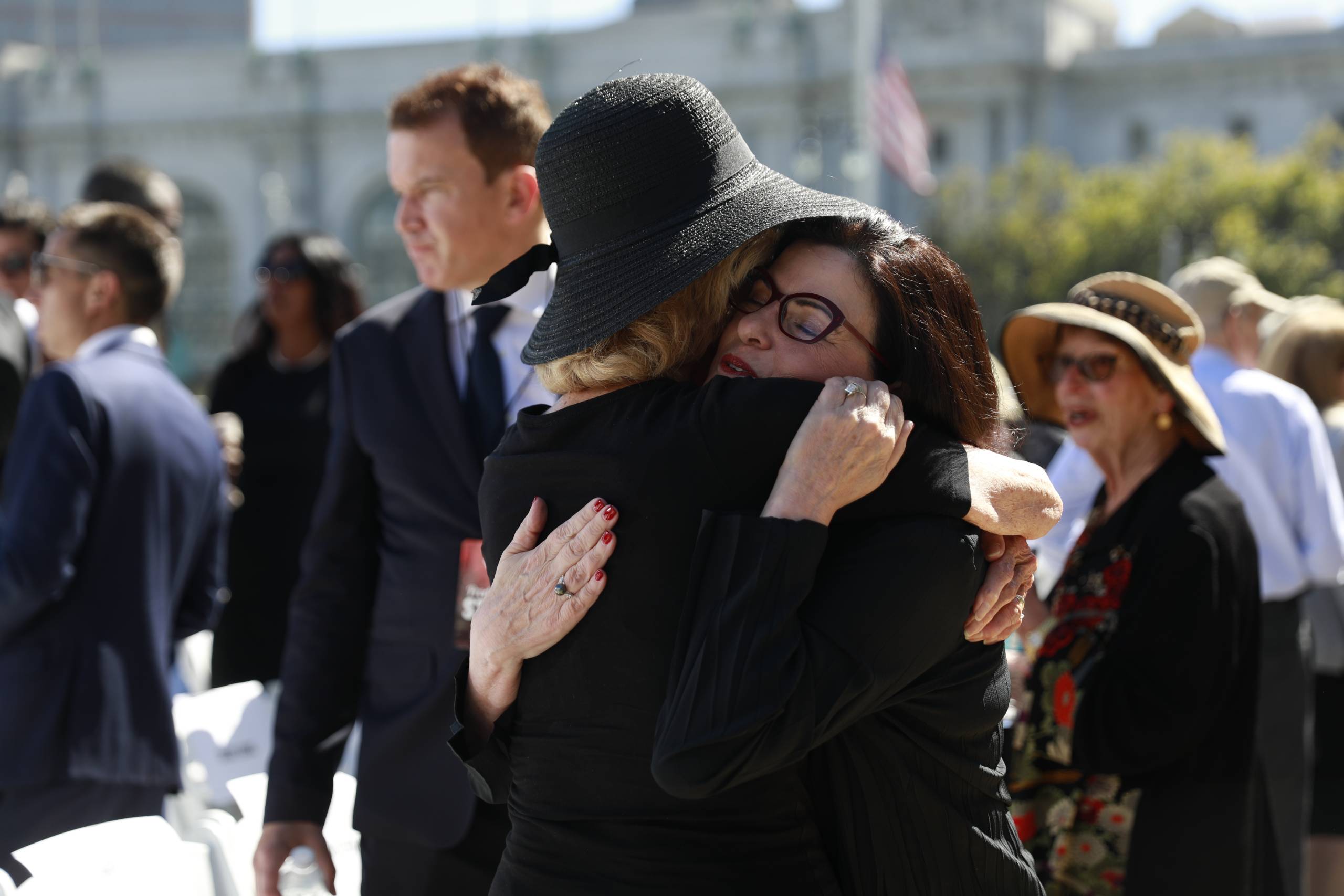 Two women hug at a memorial. 