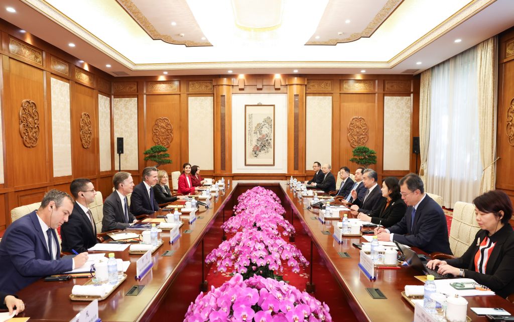 A meeting room with two delegations on either side of a long table.