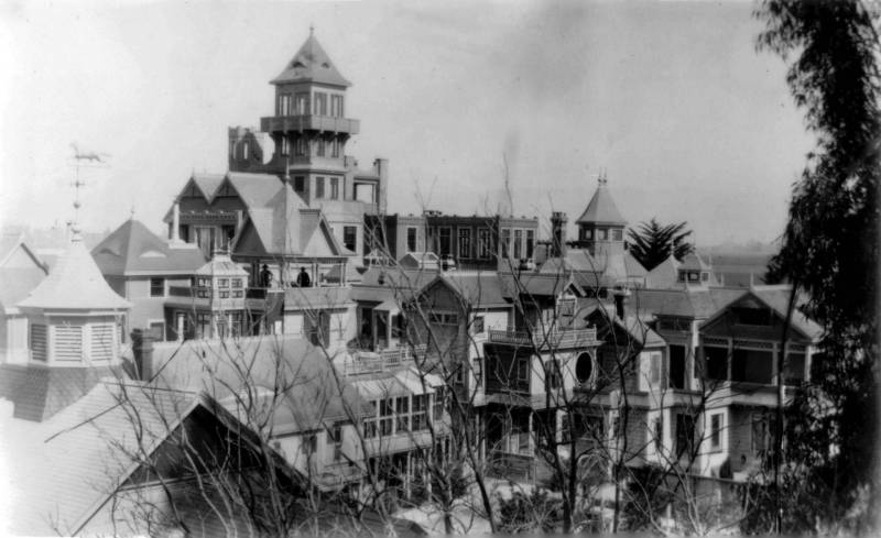 Black and white archival image of a large and sprawling mansion with many pointed towers