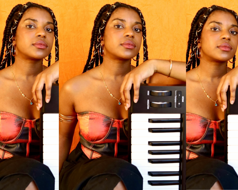 A photo collage of an African American woman with locs and a reddish top resting her arm on a keyboard.