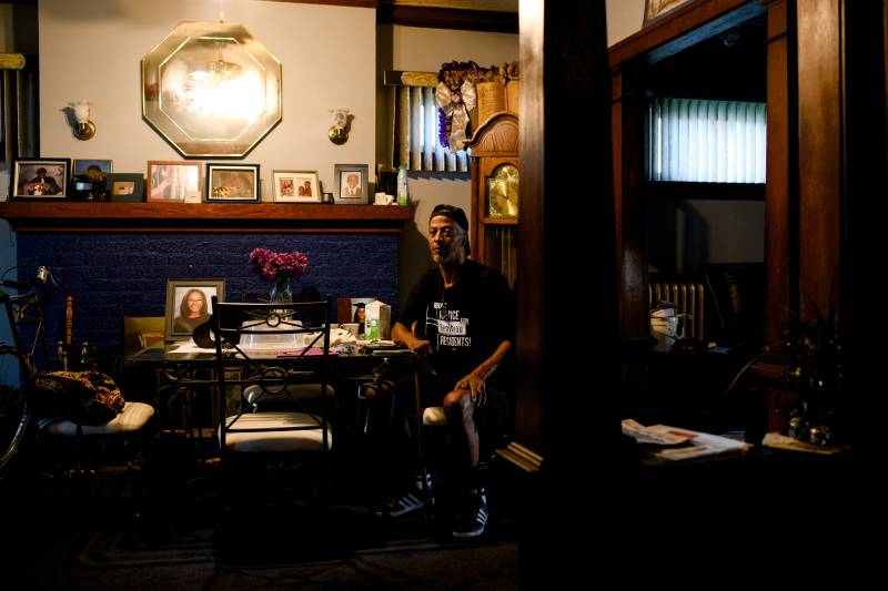 A Black man sits inside a home at a dinner table.