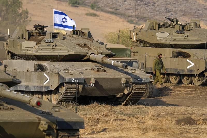 A tank with the Israeli flag is seen in the country. Soldiers stand outside of it.