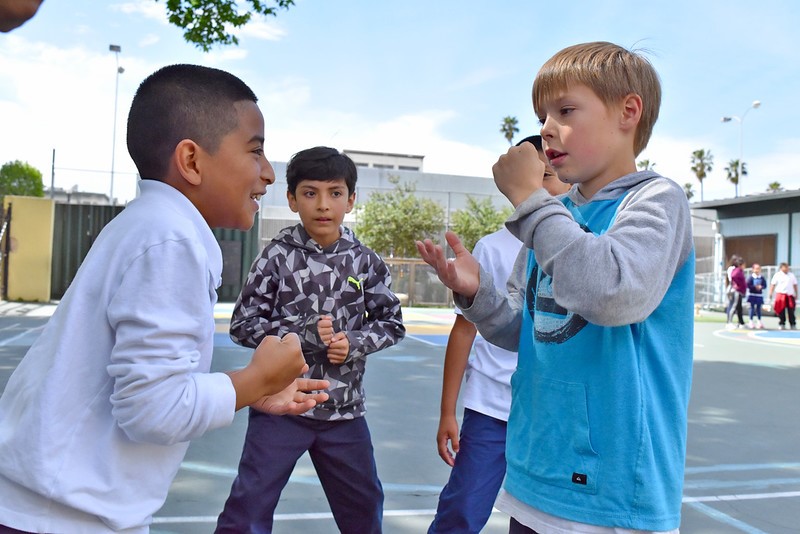 Children are playing rock, paper, scissors at recess on the schoolgrounds.