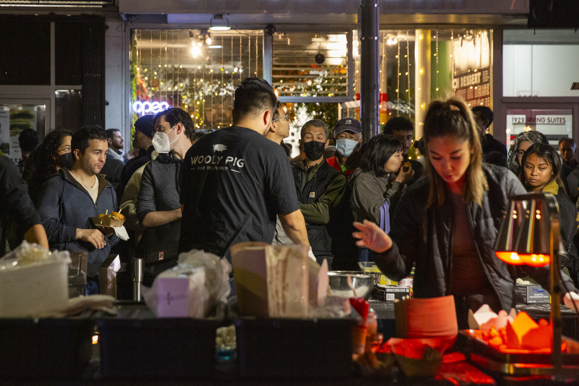 A bustling night market with food and live performances sees crowds of patrons.