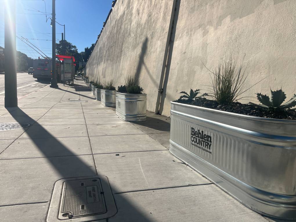 A view of planters lined up along a sidewalk.