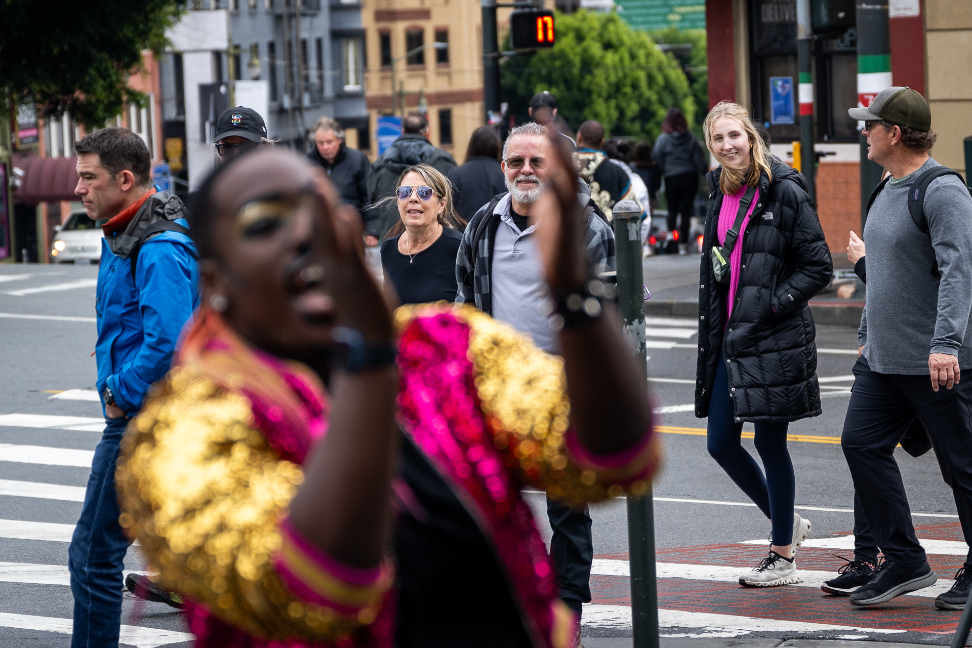 An African American drag artist performs as passersby look on and cheer.