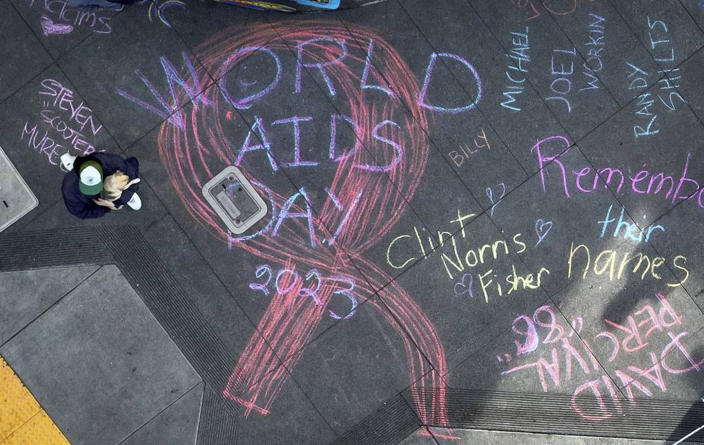 A large red ribbon and several names are written in chalk on a sidewalk.