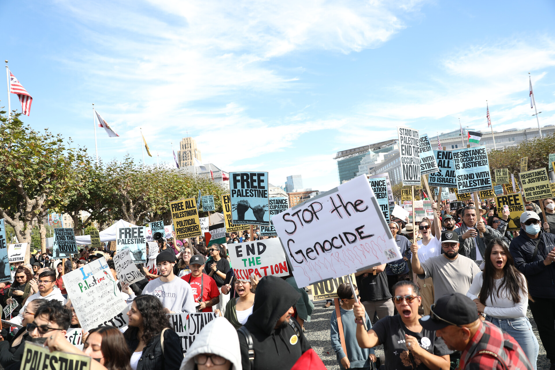 A crowd of protesters hold signs.