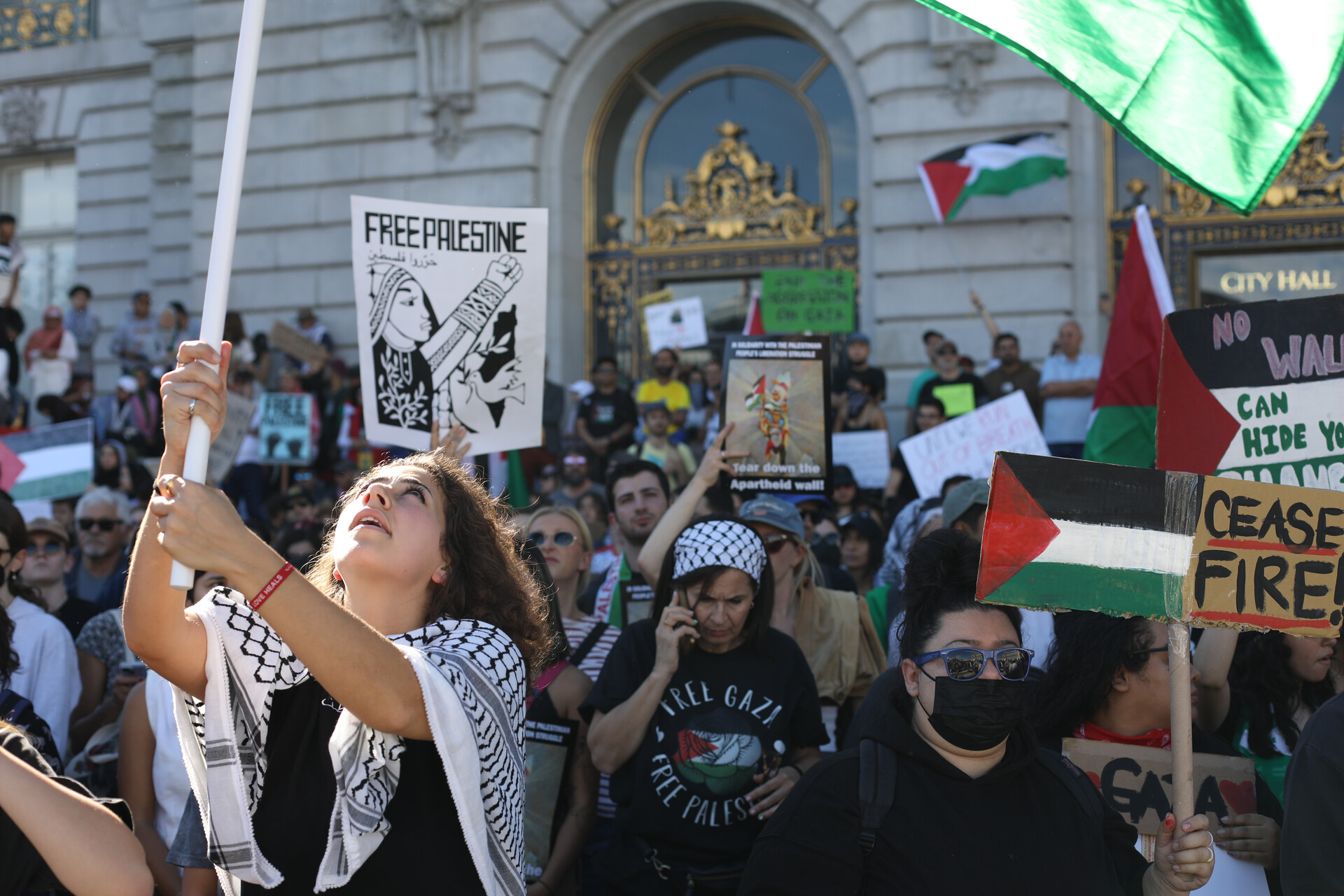 A woman waves a Palestinian flag amid a crowd of protesters.