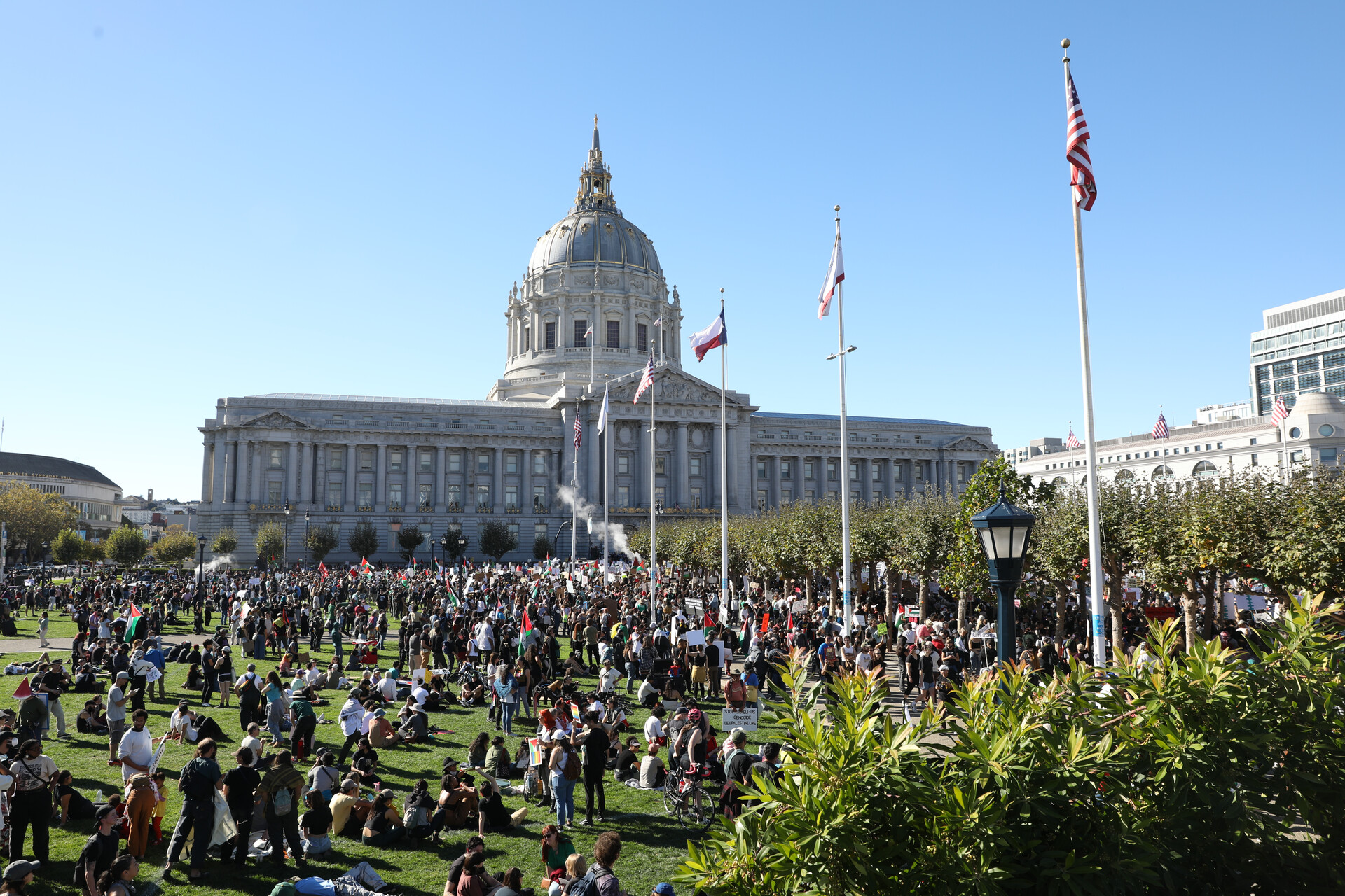 A crowd of people on the lawn in front of San Francisco City Hall in the background.