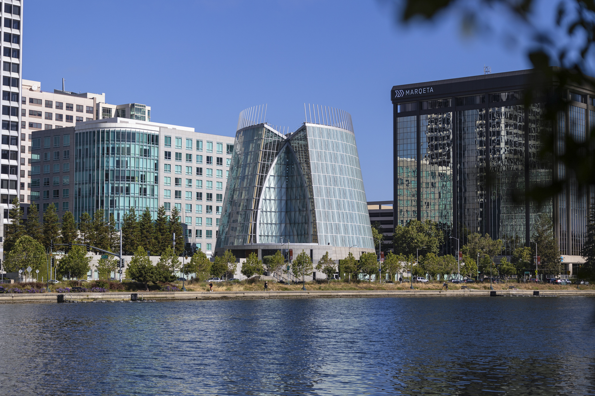 A large and circular modern-looking building sitting beside a body of water.