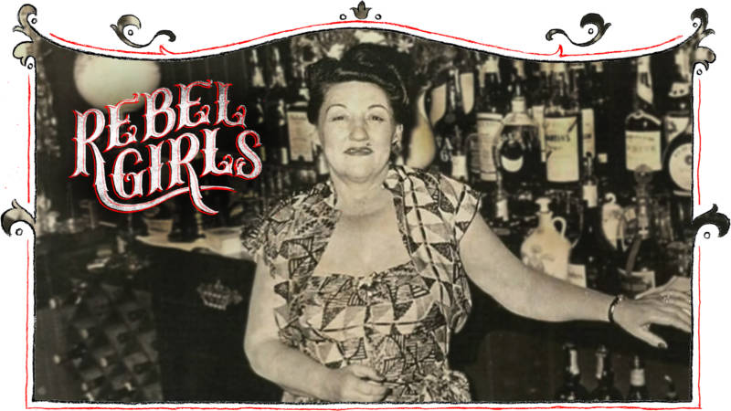 A plump smiling woman poses in front of a bar, her hair curled into a 1940s style, wearing a patterned dress and matching bolero jacket.