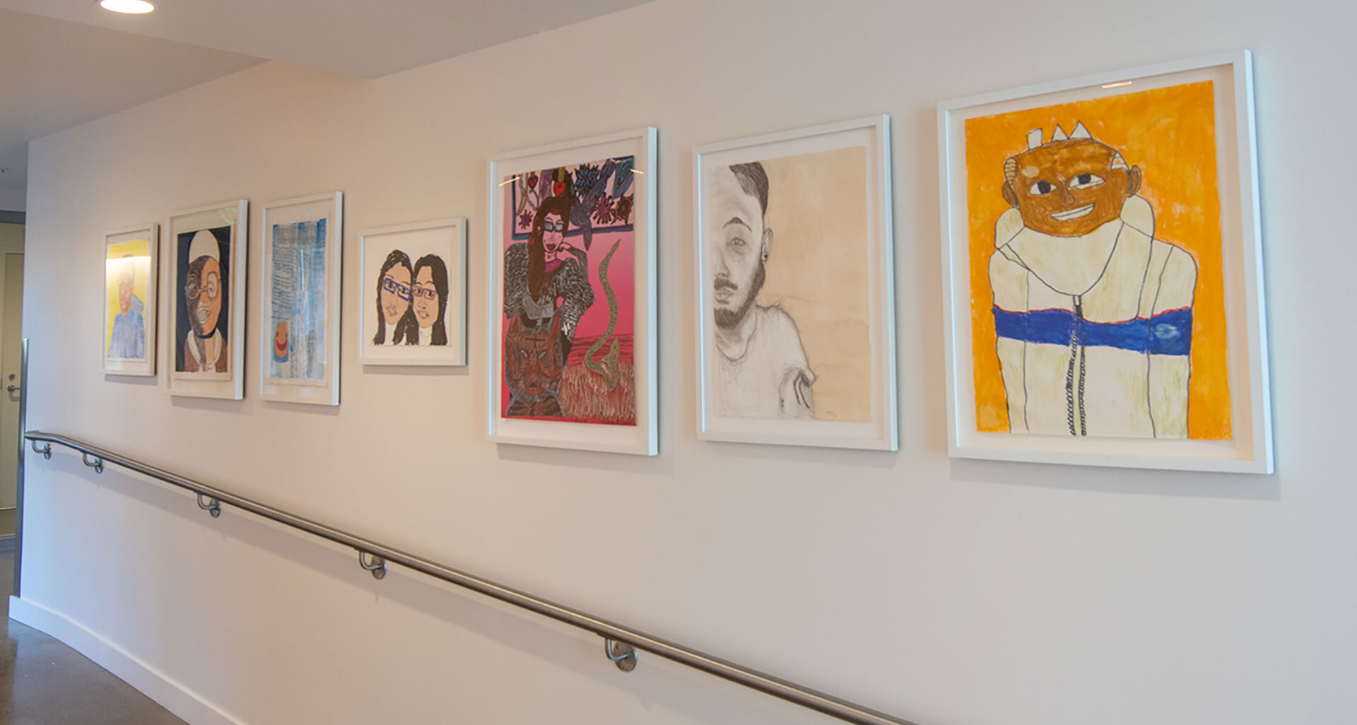 Selection of 7 self-portraits by Creativity Explored installed in the lower lobby corridor of KQED.