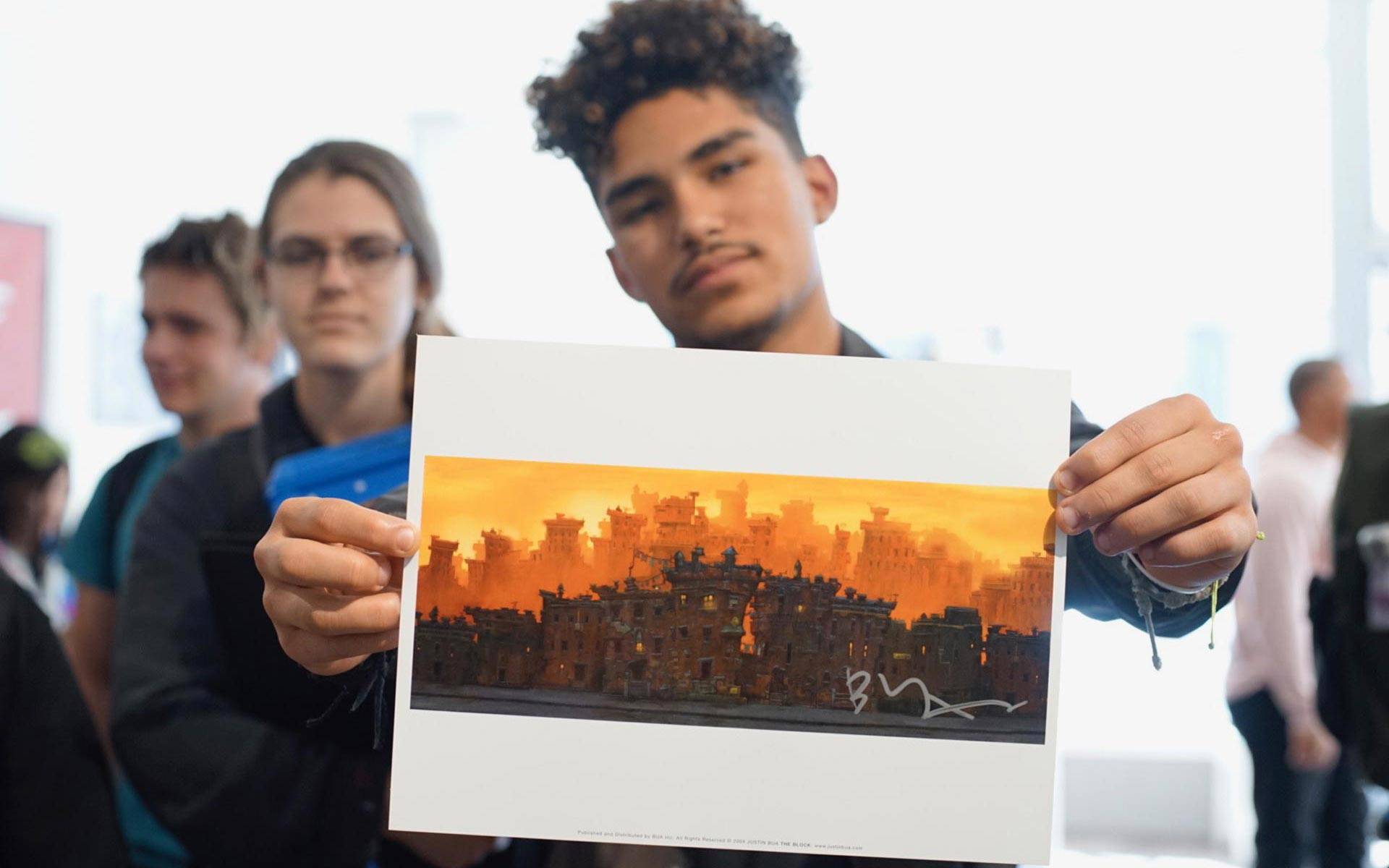 A student from Oakland School for the Arts holds up a print by artist Justin Bua. The artist appeared at SoleSpace in downtown Oakland for a talk with students. Pendarvis Harshaw