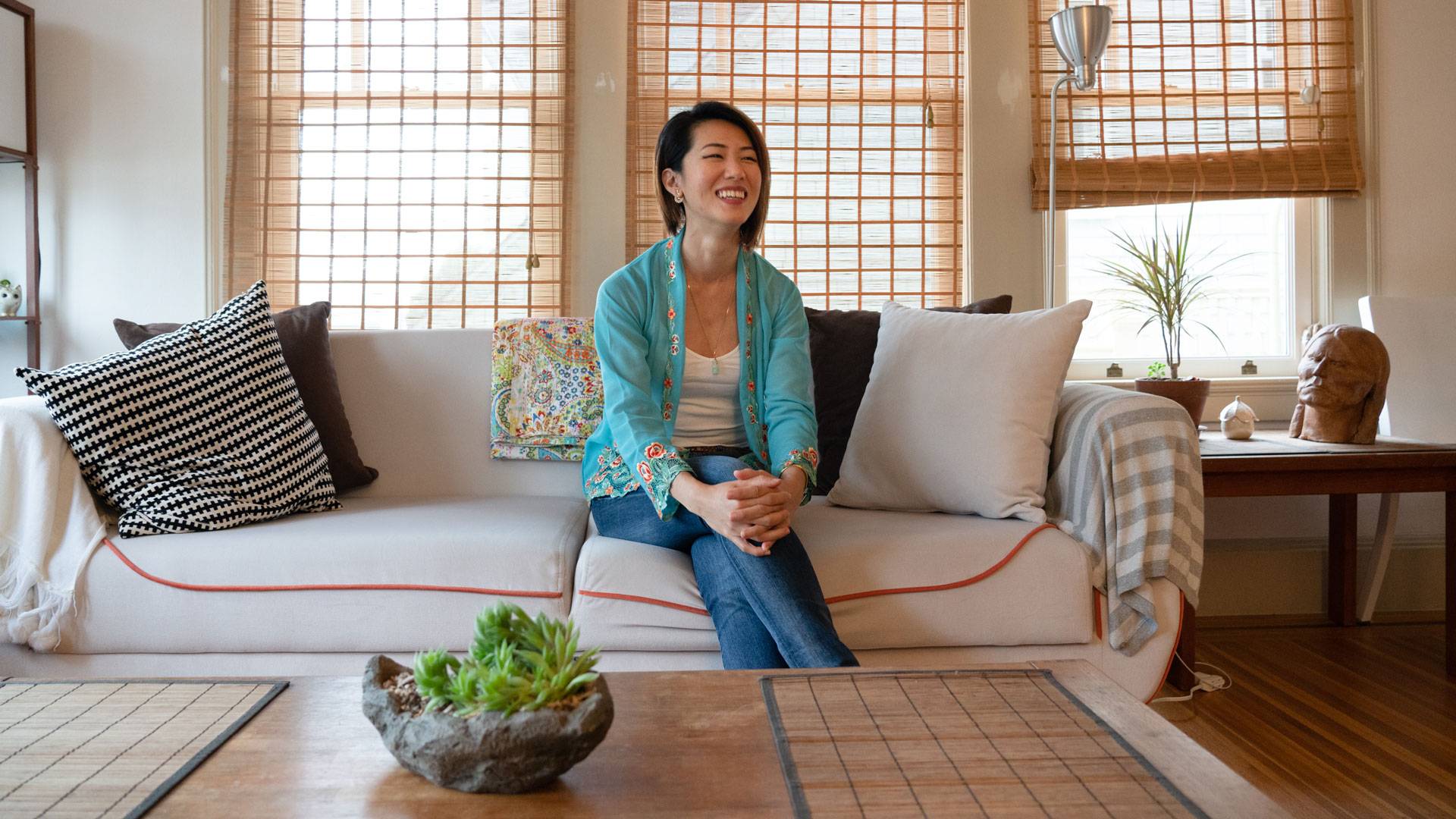 Tracy Goh at home in her Sea Cliff apartment, on the couch that doubles as her office.  Graham Holoch/KQED