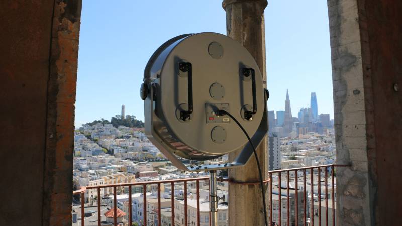 The back of a round speaker points out at San Francisco from SFAI's bell tower.