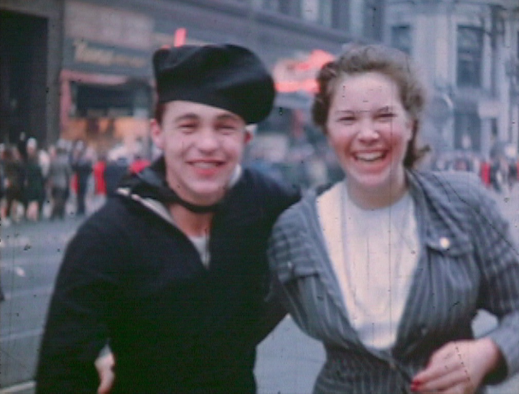 A man in uniform and a woman smile on Market Street in celebration.