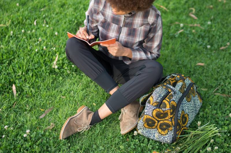 A woman writes in her diary on a lawn.