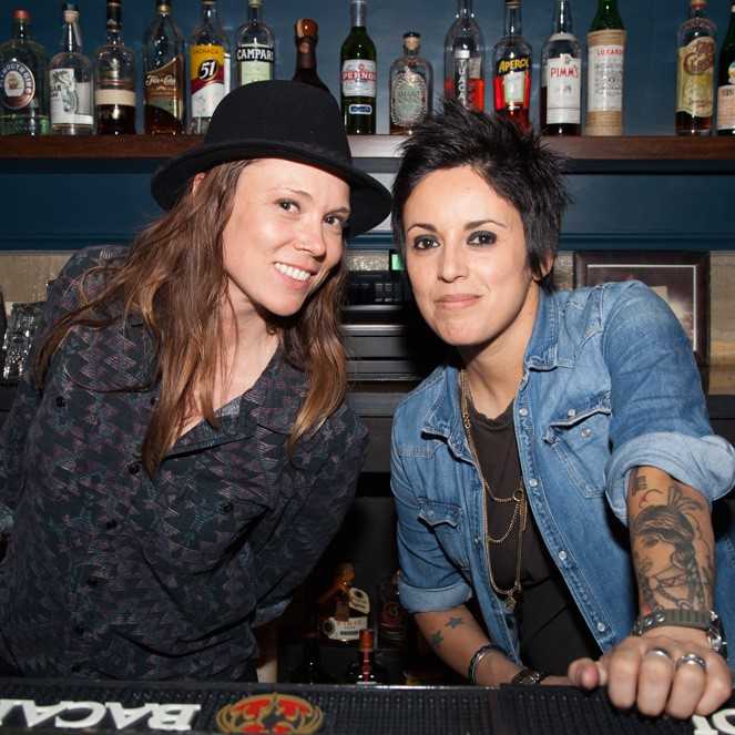 Two women pose in front of a bar.