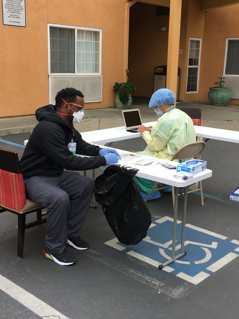 Dr. Damon Francis, in full-body scrubs, doing COVID-19 testing at Operation Comfort, one of the isolation hotels in Oakland. (The other person in the photo is his colleague, Lafayette Bickham, a community health outreach worker at Alameda Health System.)