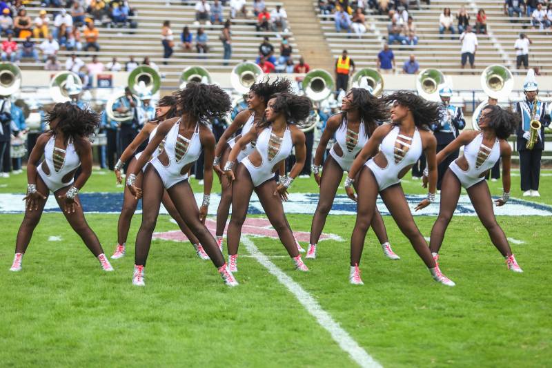 The Prancing J-Settes, the majorettes of the Jackson State University, pose in matching silver bodysuits on a football field.