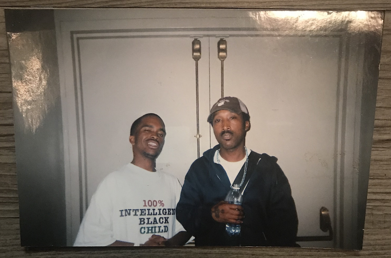 Pendarvis Harshaw wearing a "100% Intelligent Black Child" shirt while standing next to D'Wayne Wiggins backstage at the S.O.S. Hurricane Katrina Benefit Concert in Oakland.