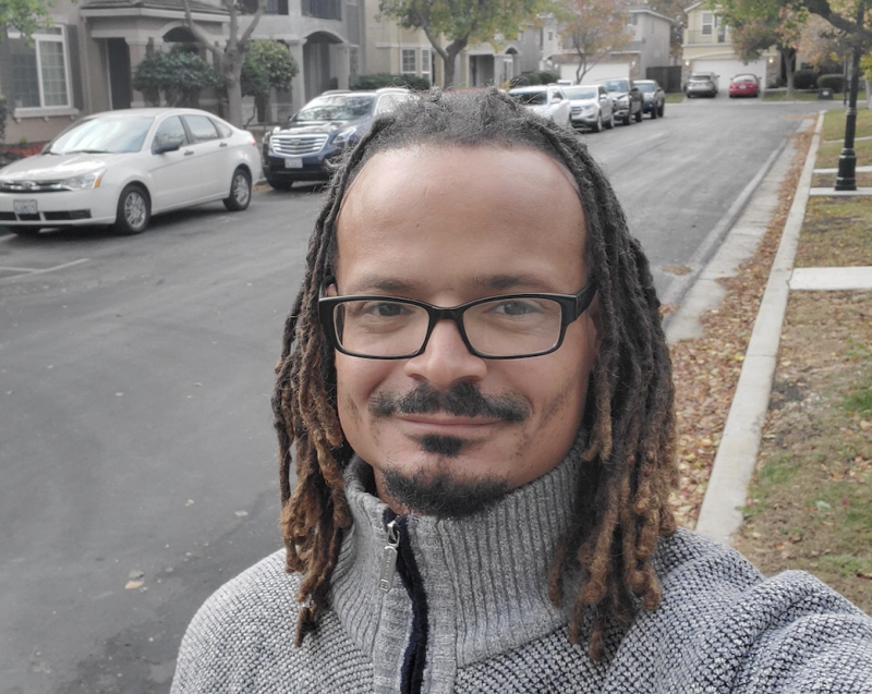 Vincent-Ray Williams III wears a grey sweater and glasses as he poses for a photo on the street.